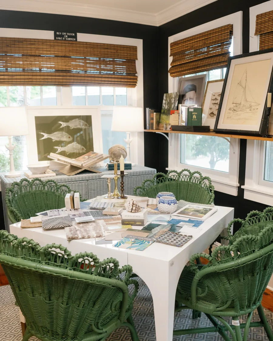 A dark-walled corner of the shop hung with framed pencil sketches, a lamp and a green wicker chair